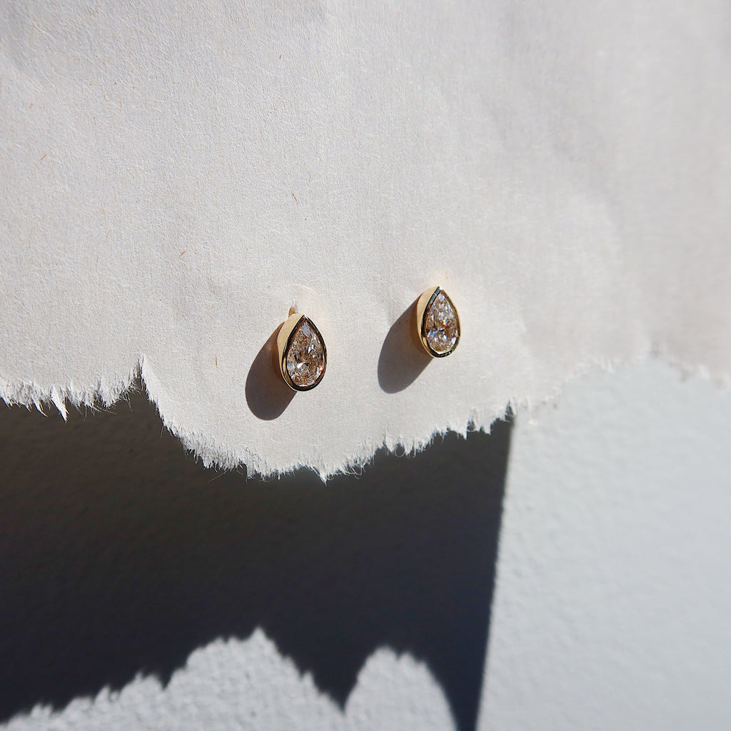 Pair of gold earrings on a textured white surface_Yellow_Gold_White_Gold
